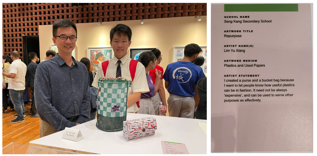 Two men stand beside a display table holding woven plastic bag artworks at a school art exhibition.